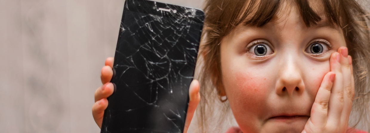 Meisje is geschrokken en heeft een mobiele telefoon in haar hand waarvan het glas gebroken is